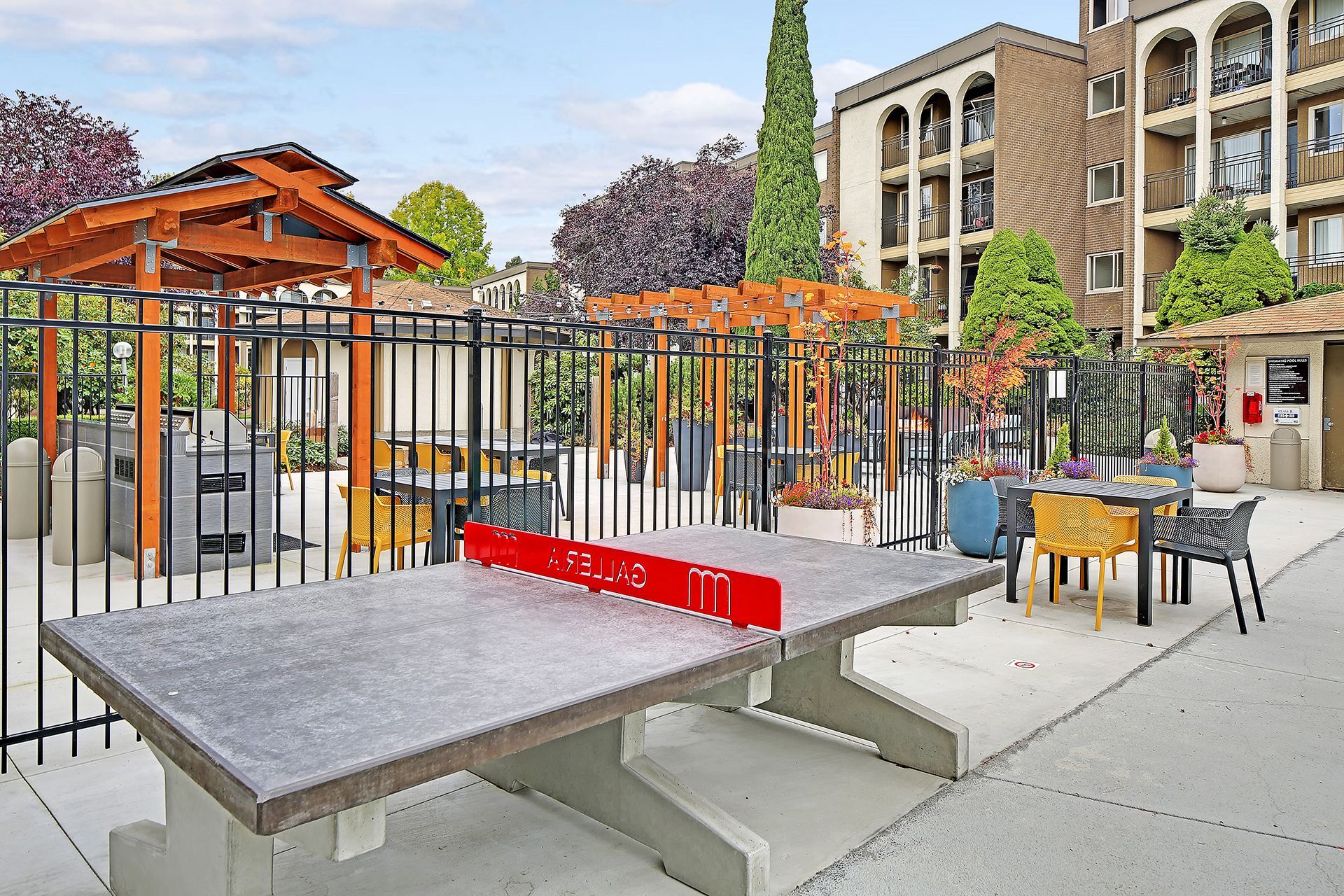 A ping pong table is sitting in front of a fence in a park.