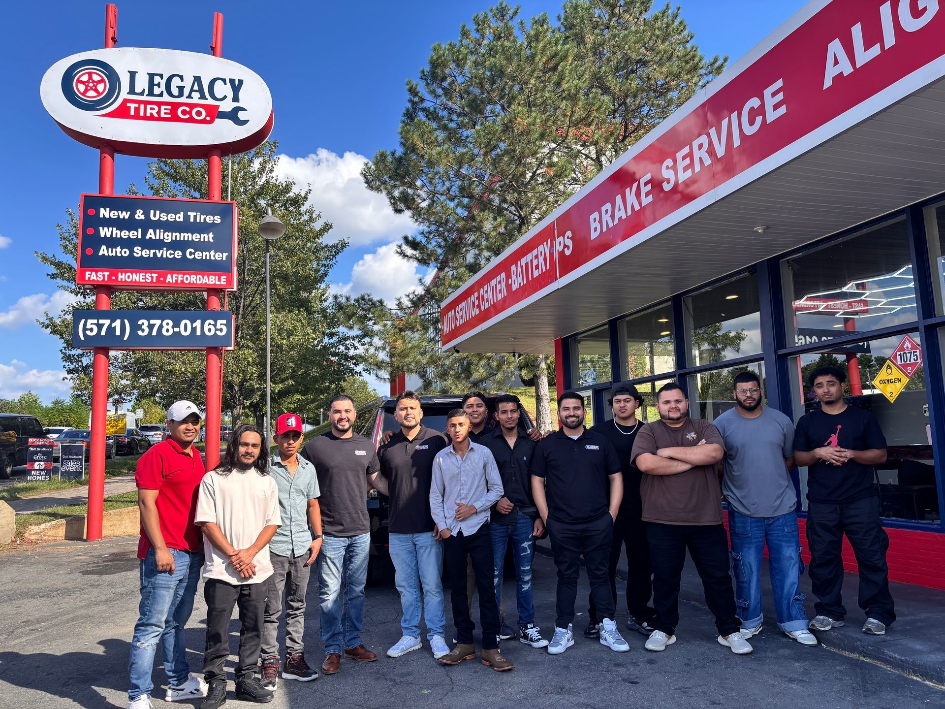 Four men watching TV in a modern room with black floors, a hexagon light fixture, and large windows | Legacy Tire Company