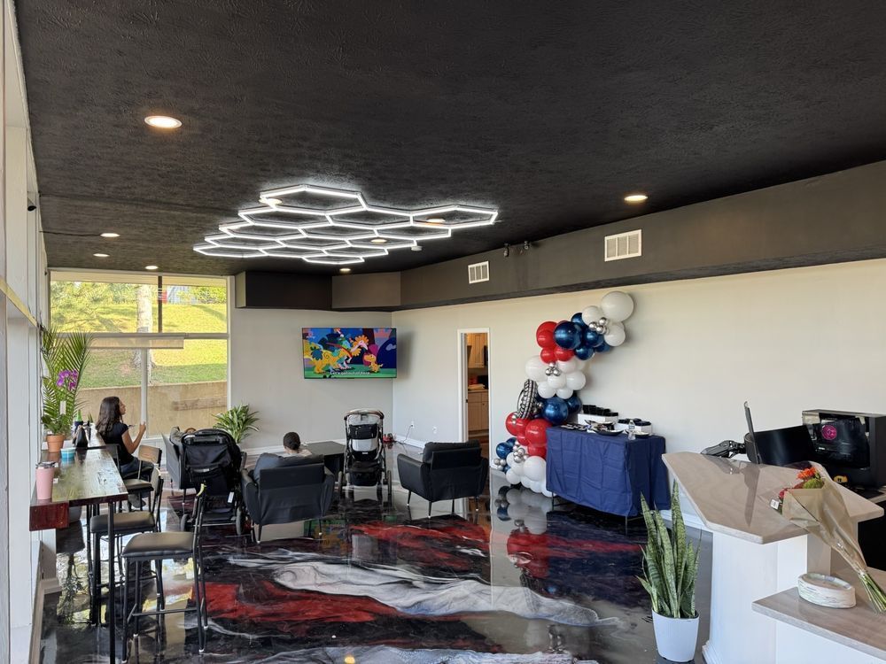 Interior with black ceiling, hexagon lights, and shiny red, black, and white floor. People and balloons are present | Legacy Tire Company