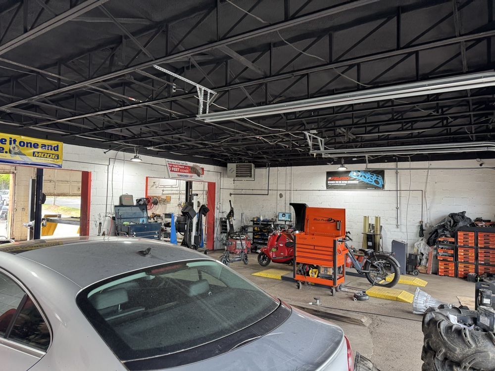 An auto repair shop with a silver car, tools, and equipment; a motorcycle is visible | Legacy Tire Company