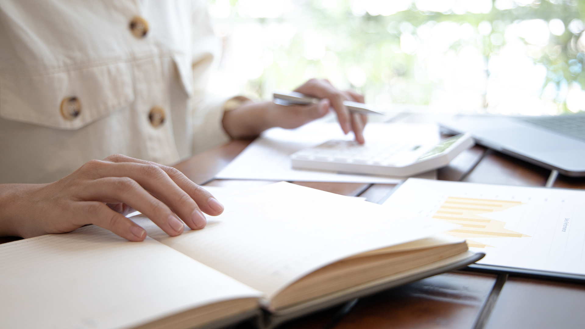 A woman is sitting at a table writing in a notebook.