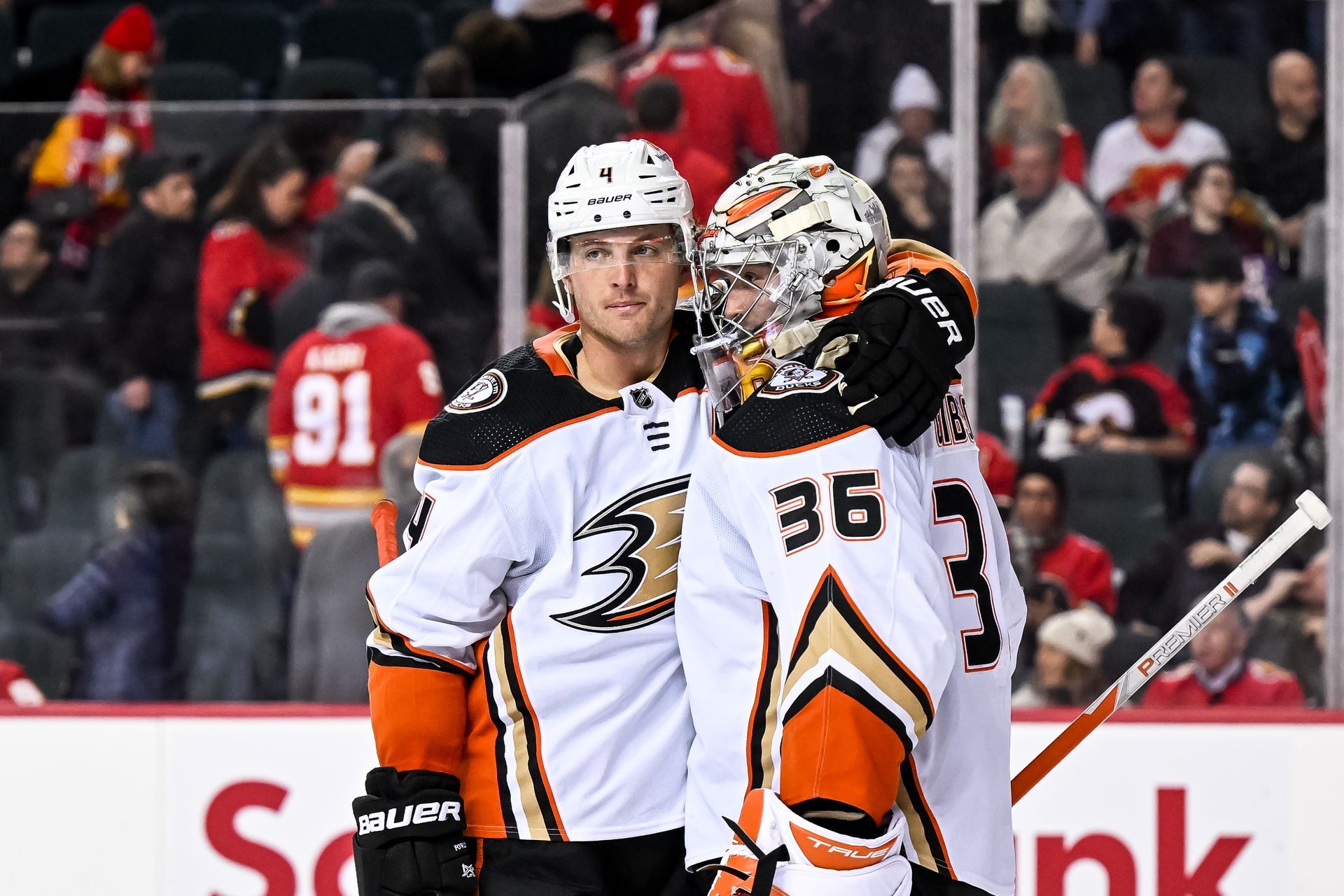 two Anaheim Ducks hockey players are hugging each other on the ice .