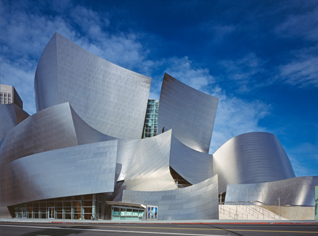 a large stainless steel building with a blue sky in the background, it's the Walt Disney Concert Hall.