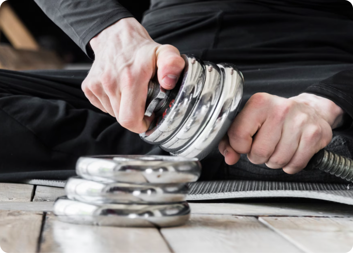 Person using a hand grip strengthener over stacked metal spring devices on a wooden table