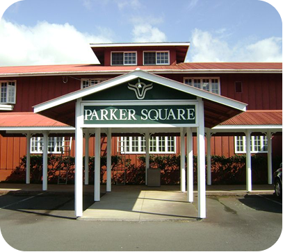 Parker Square entrance with red barn-style building and white columns under a blue sky