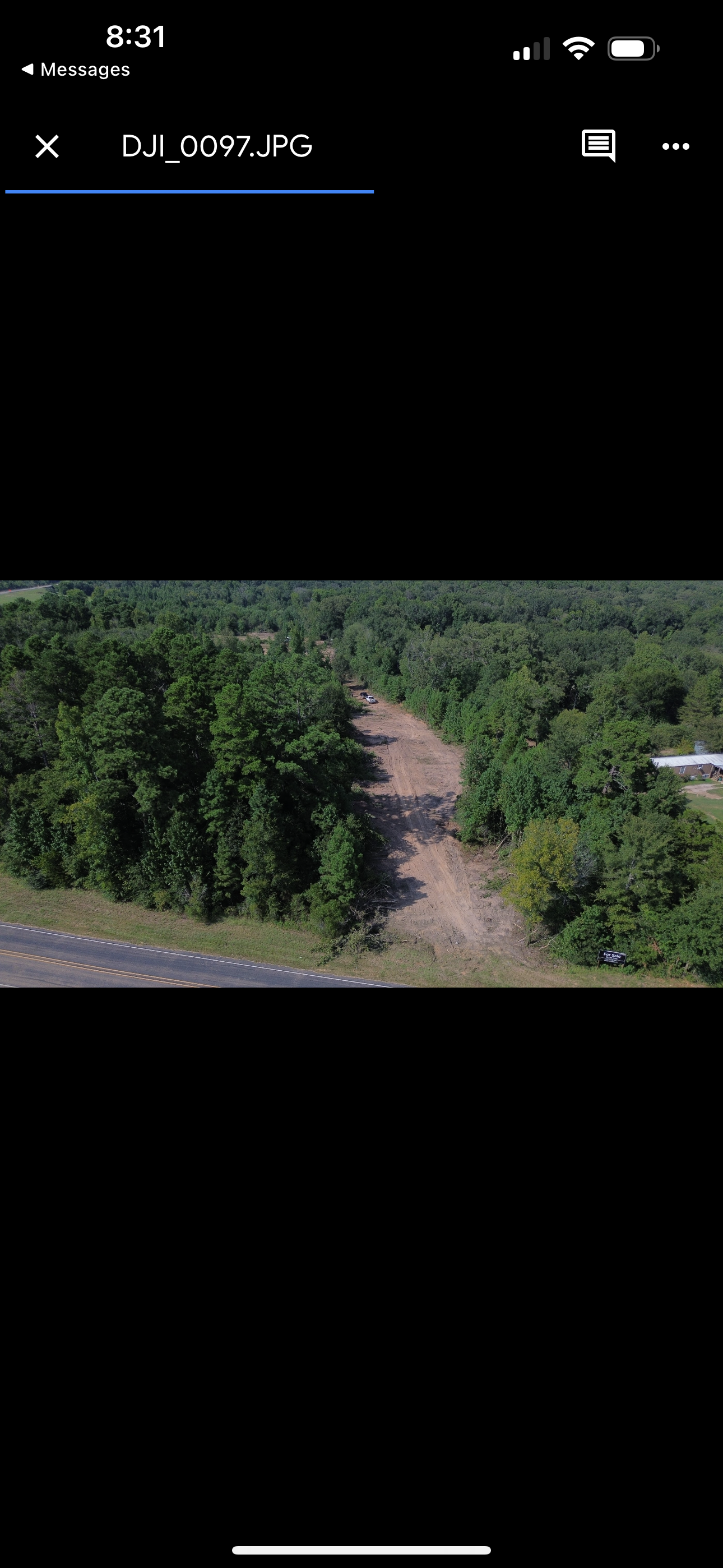 Aerial view of a dirt path cutting through a forest.