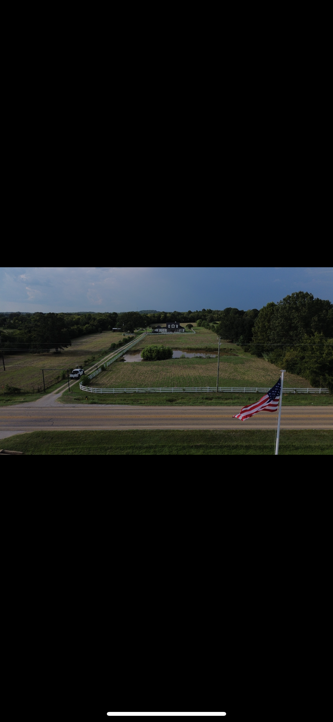 An aerial view of a field with a road and an American flag.