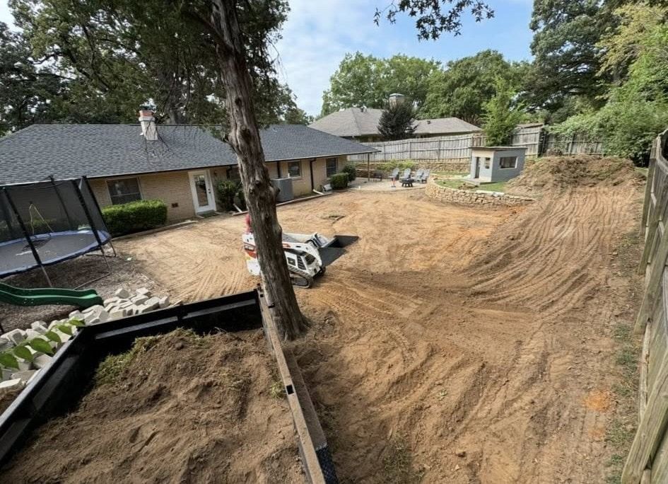 Backyard being renovated with dirt piles, a small building, and a trampoline.