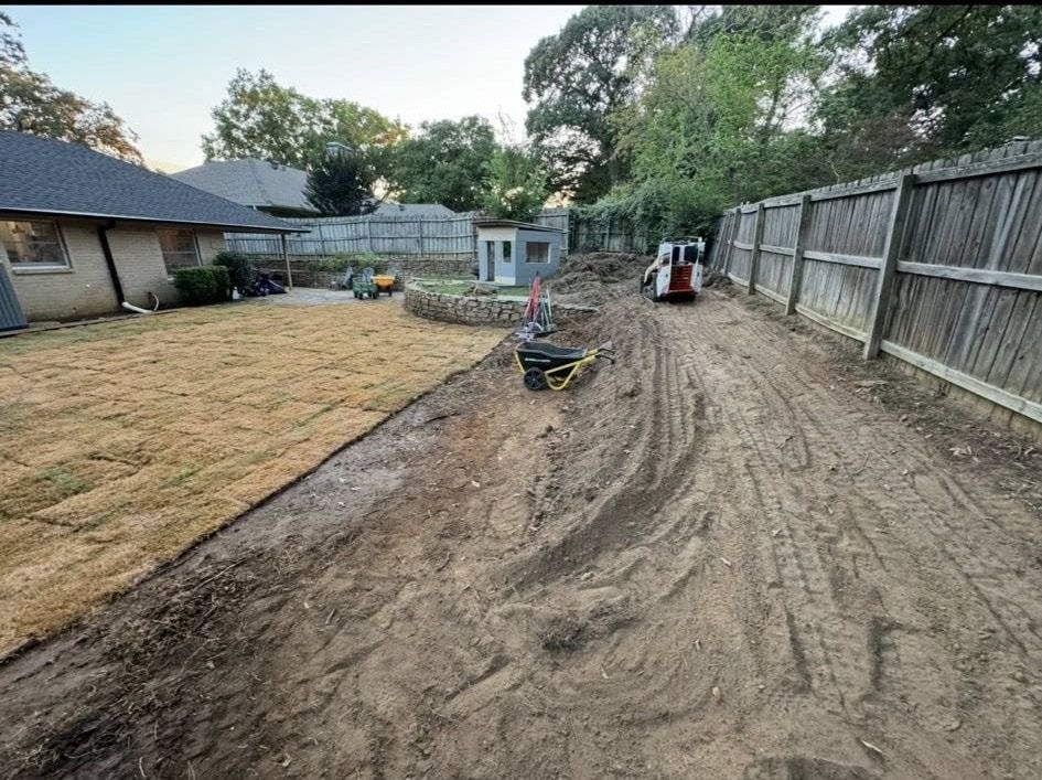Backyard with new sod, dirt path, small equipment, and a wooden fence.