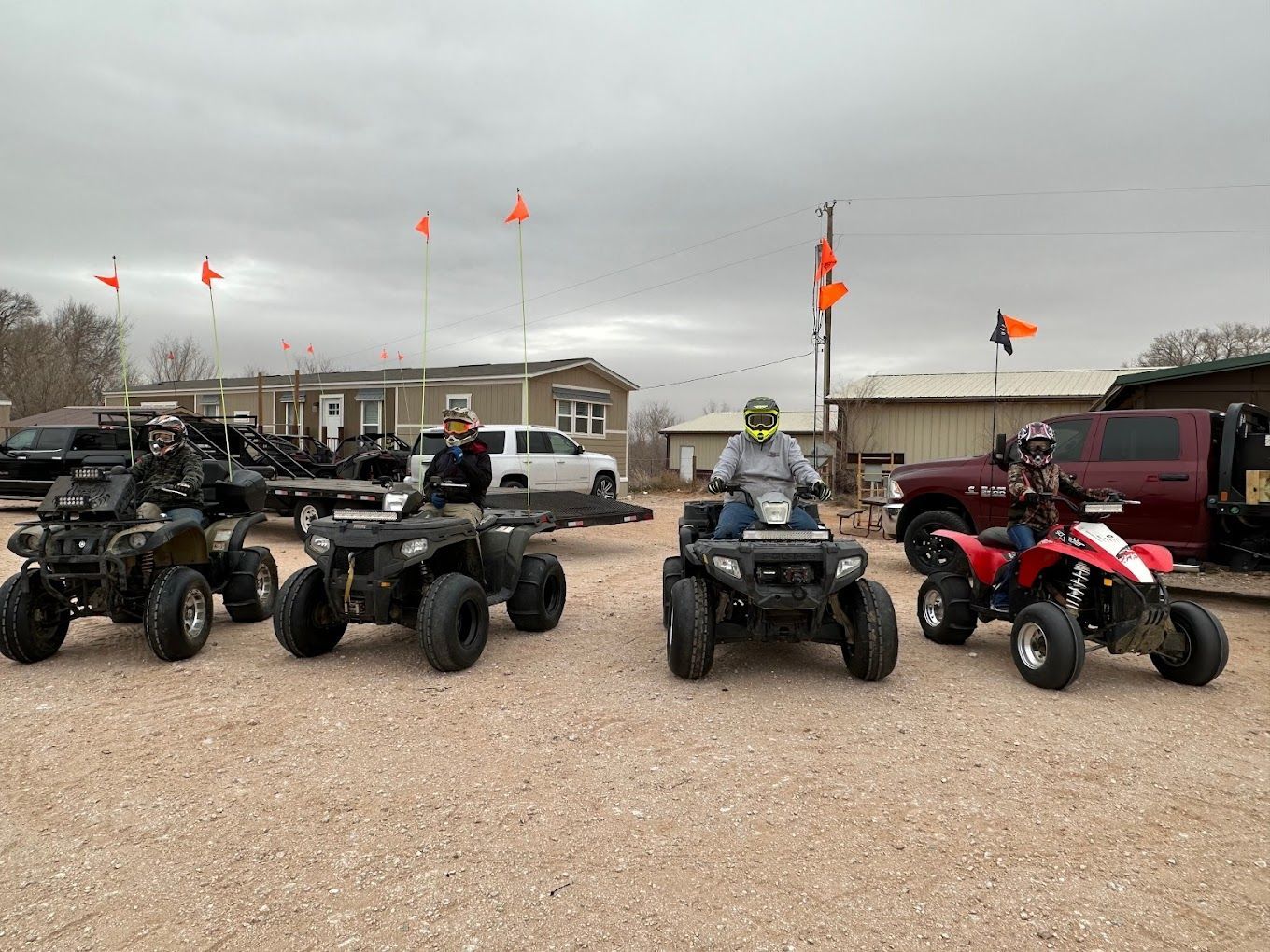 A group of people are riding atvs in a gravel lot.