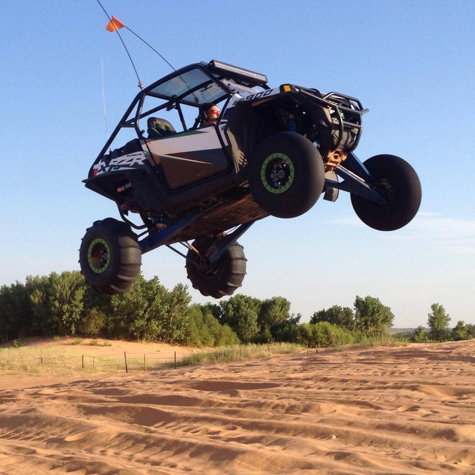 A vehicle is flying through the air on a dirt road