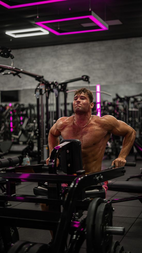 A shirtless man is standing on a machine in a gym.