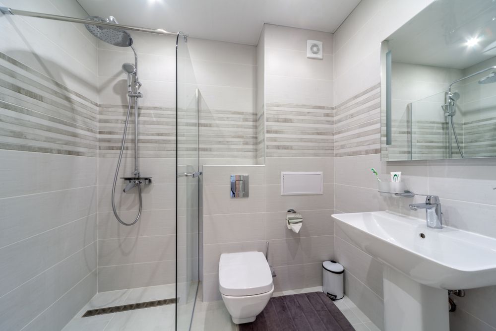 A Bathroom With A Toilet, Sink, Shower And Mirror — Harris Design & Building Concepts In Proserpine, QLD