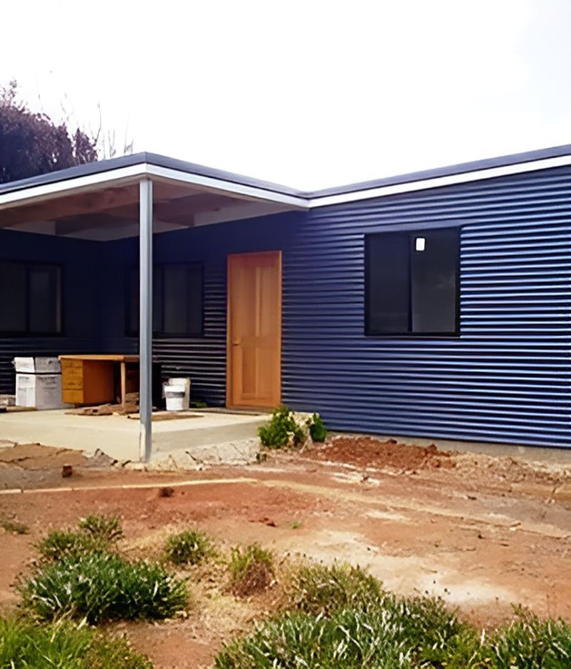 A Blue House With A Porch And A Wooden Door — Harris Design & Building Concepts In Jubilee Pocket, QLD