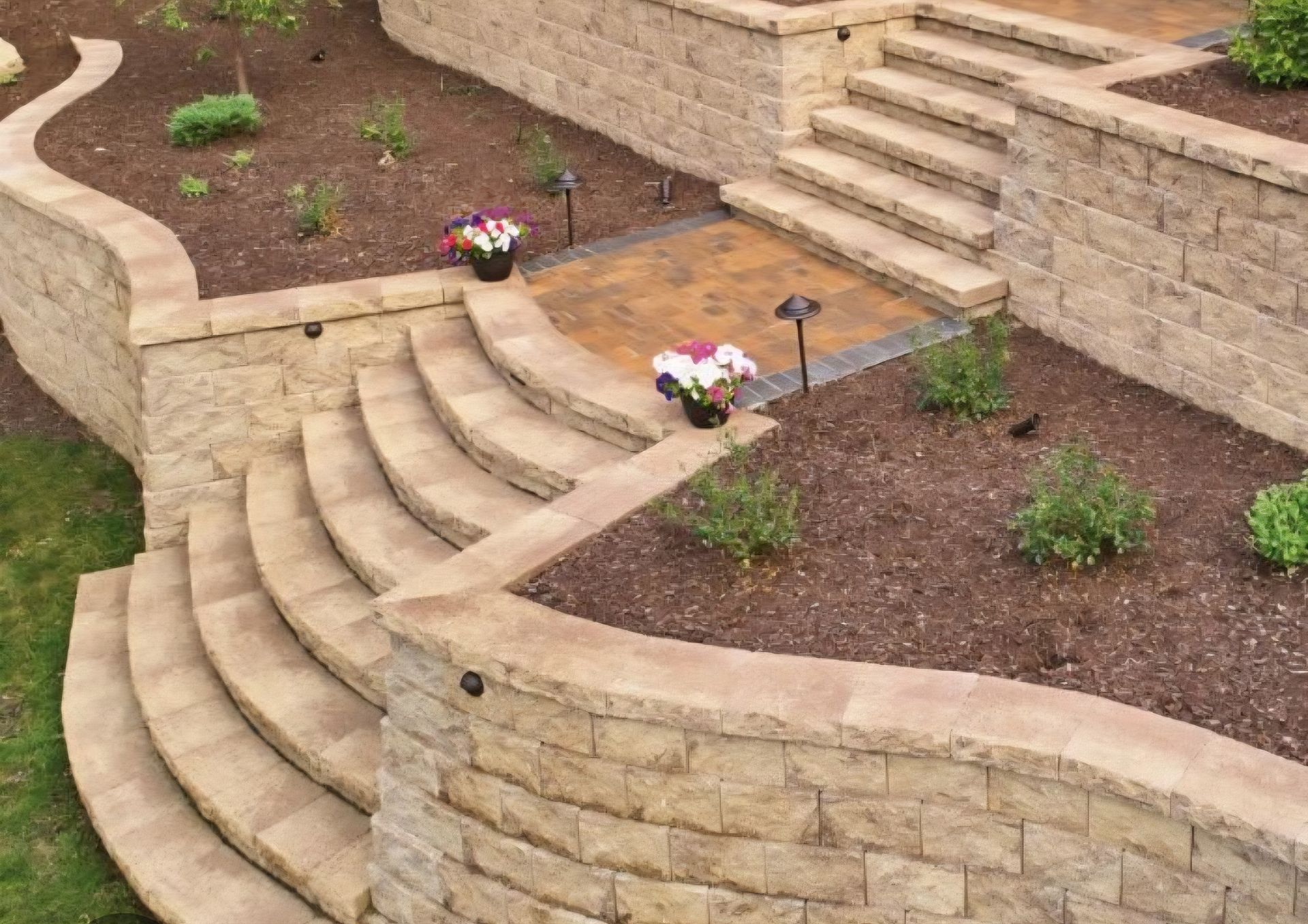Curved stone staircase and retaining walls with landscaped beds.