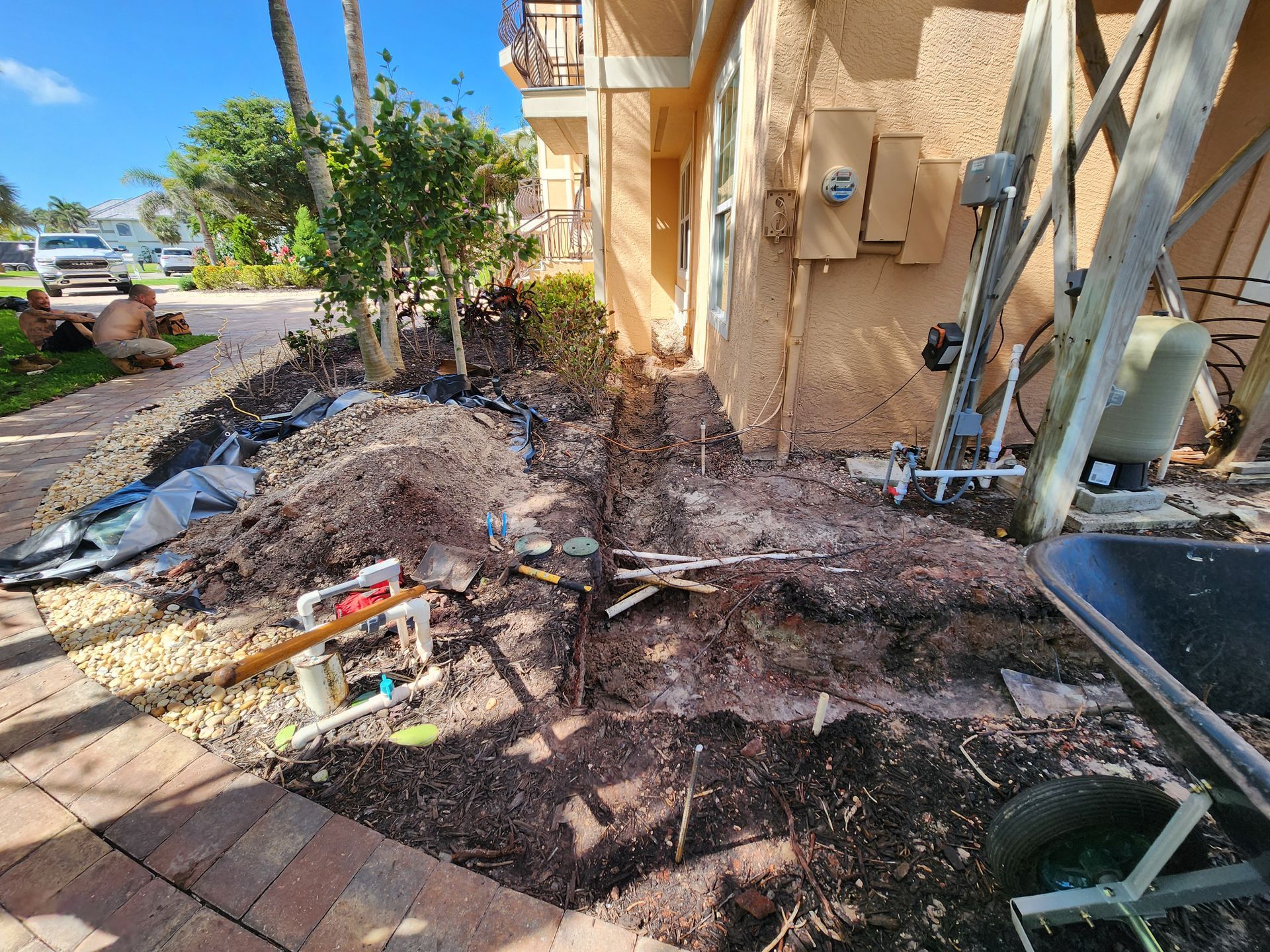 A wheelbarrow is sitting next to a pile of dirt in front of a house.