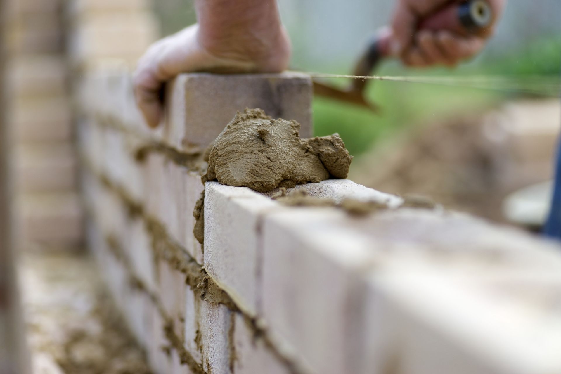 A man is laying bricks on a wall with a trowel.
