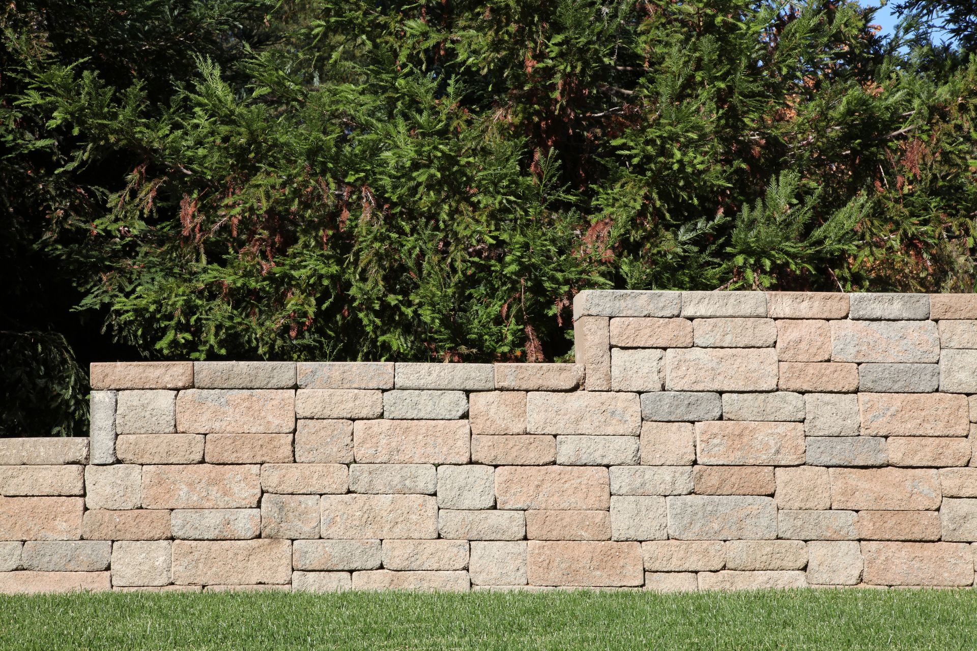 A brick wall is sitting on top of a lush green field.