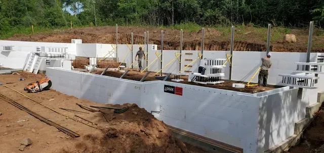 A large white wall is being built on top of a dirt field.