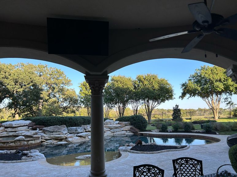 A patio with a pool and a ceiling fan