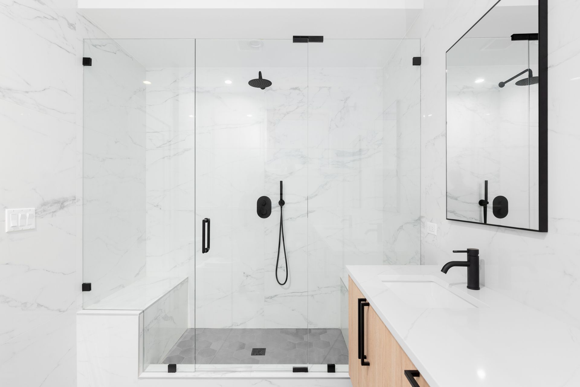 A bathroom with a walk in shower , sink and mirror.