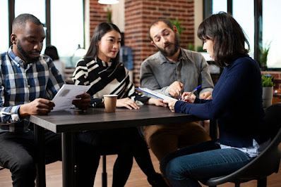 Four people at a table, reviewing documents in an office setting.