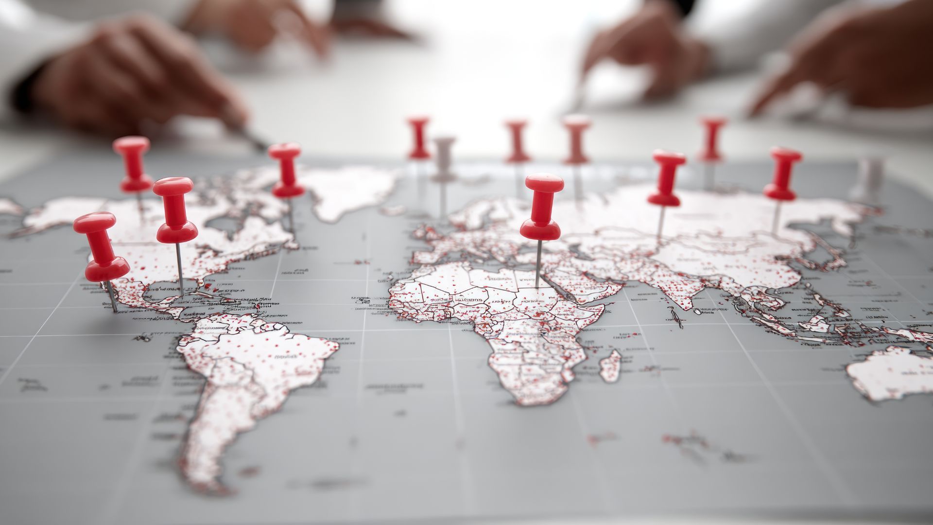 World map with red pins; people pointing at it.