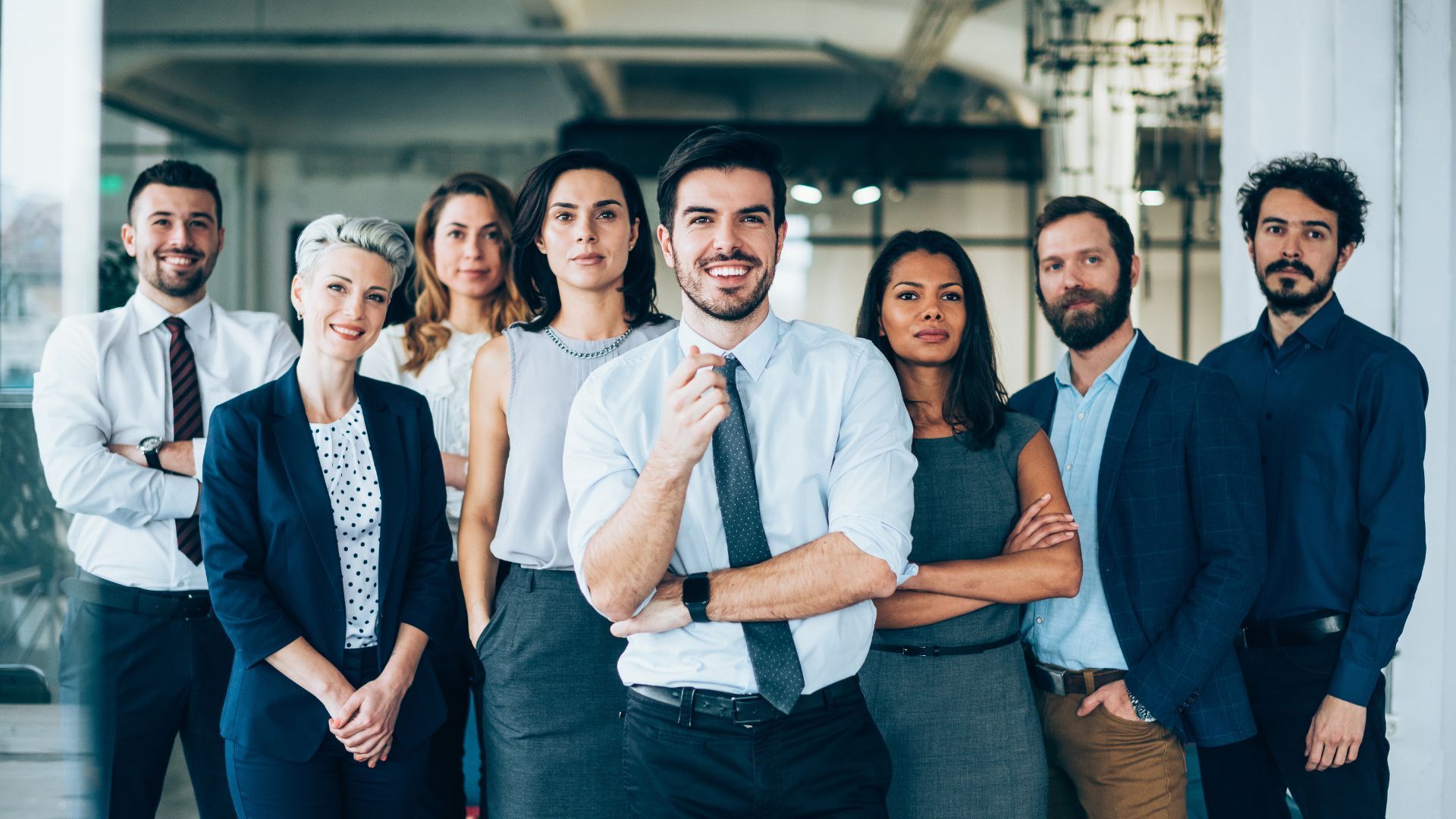 Group of diverse professionals posing confidently indoors.
