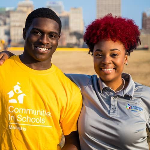 Two people smile, one in a yellow