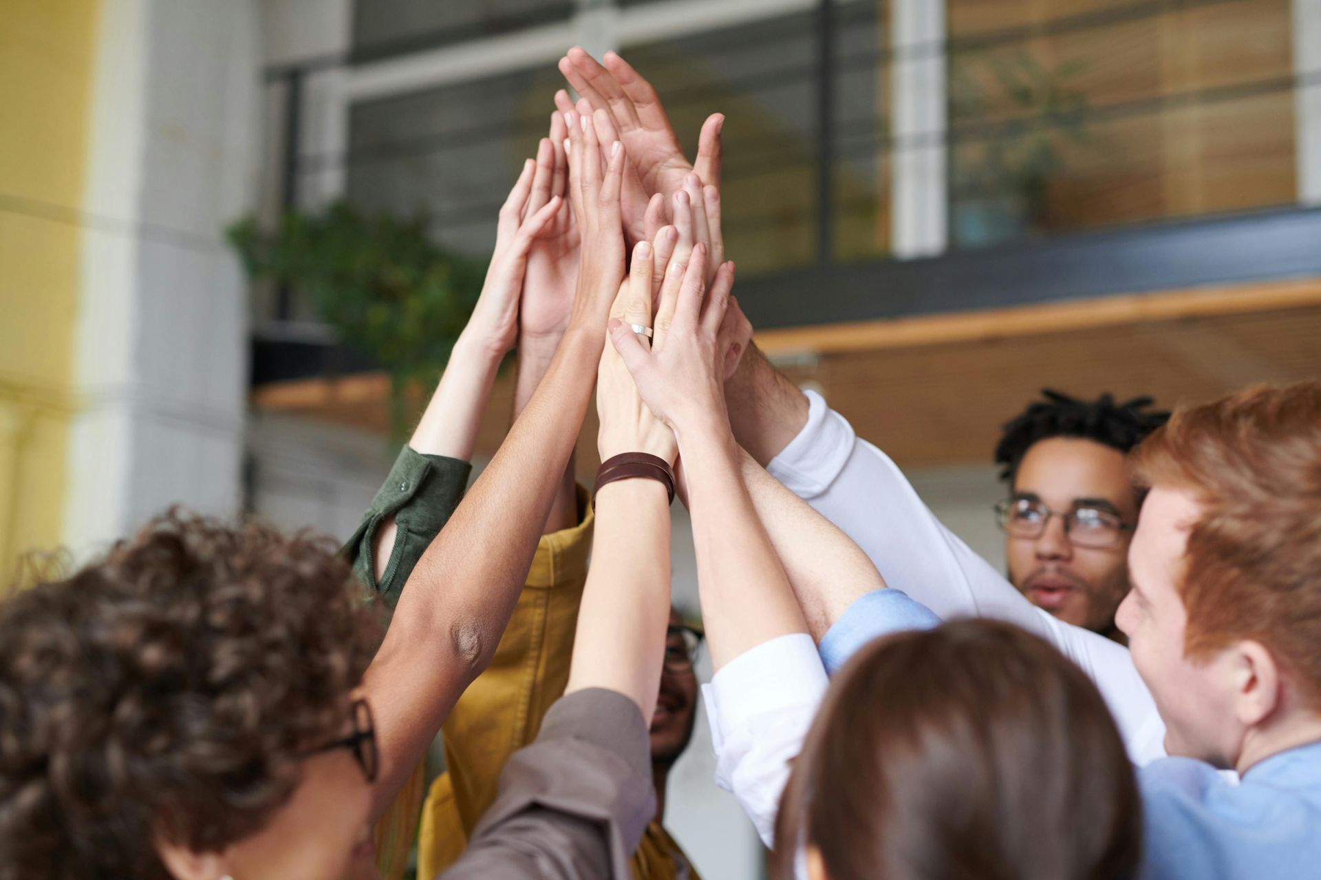 People with hands raised together in a high five, celebrating a group achievement.