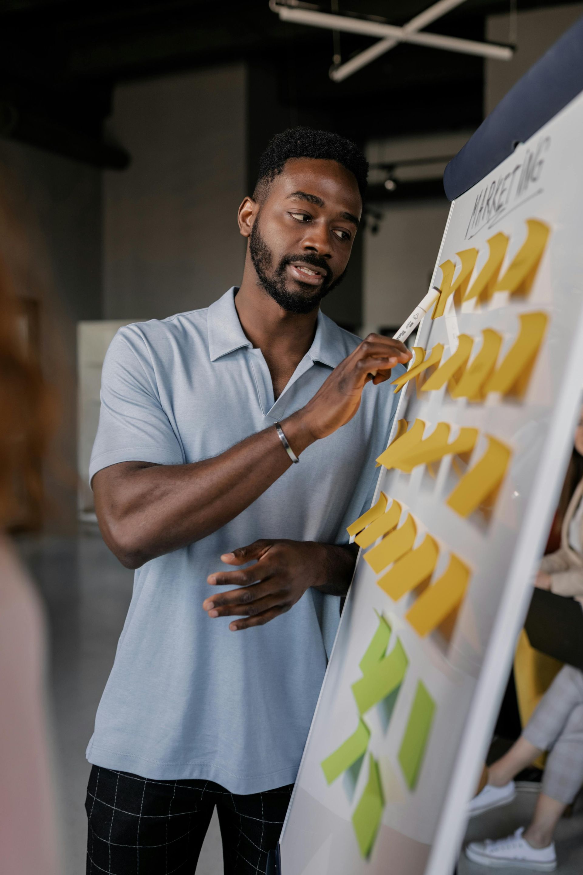 Man pointing to sticky notes on a whiteboard during a meeting.