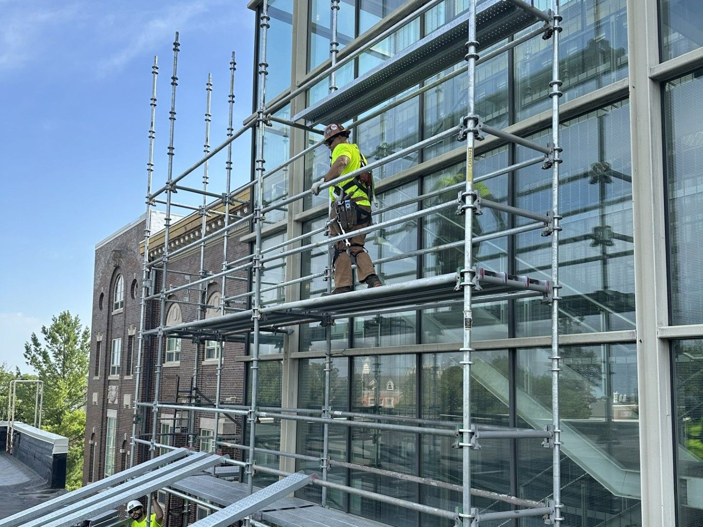 Two construction workers are working on a roof on a scaffolding. Two construction workers are working on a roof on a scaffolding.