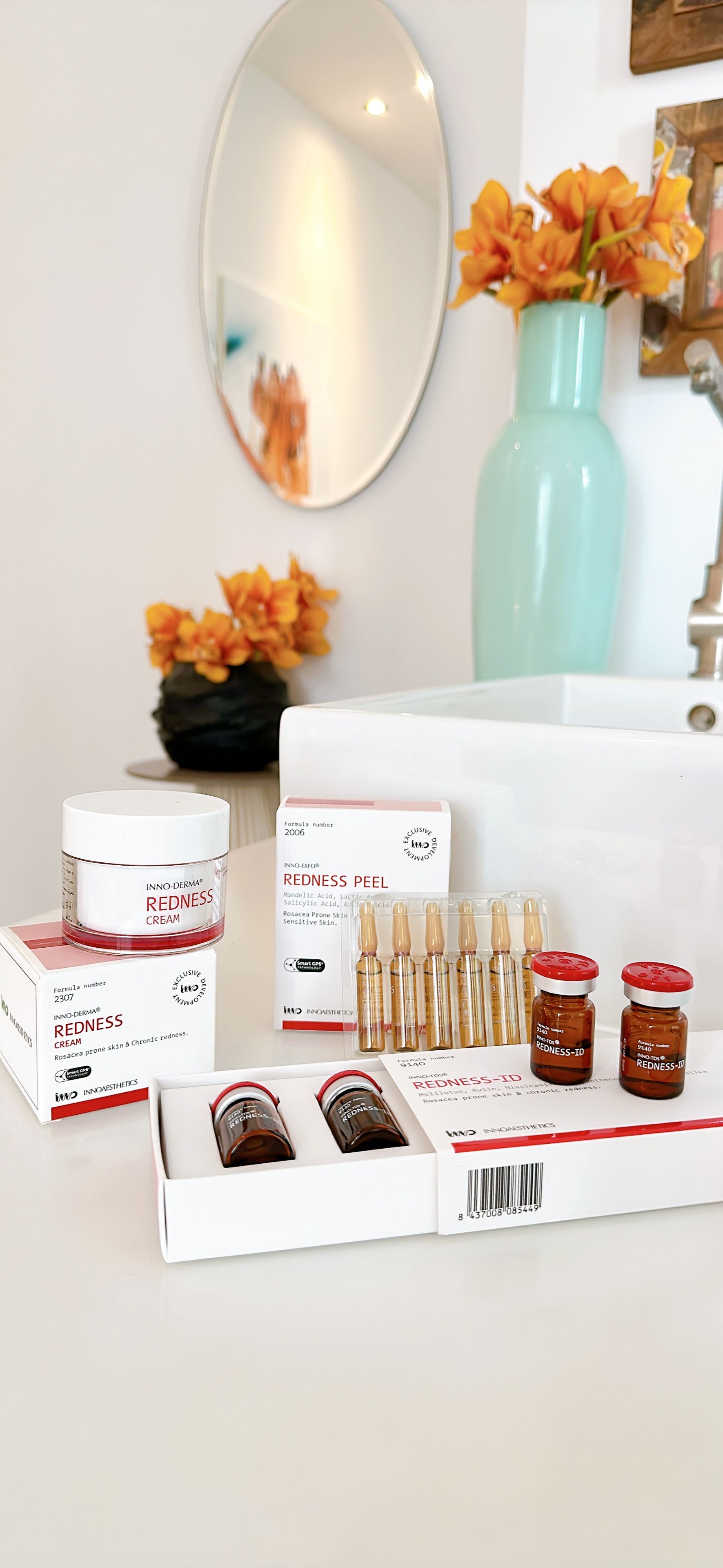 Ein Badezimmer mit Waschbecken, Spiegel und Blumenvase.