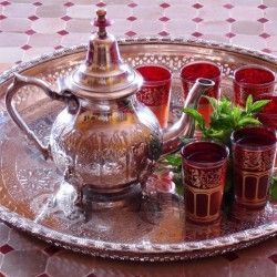 Een theepot en kopjes staan ​​op een dienblad op een tafel.