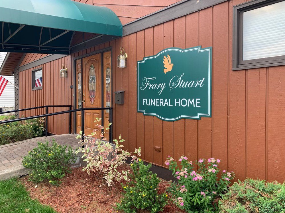 The Frary Stuart Funeral Home building with wood-paneled exterior, green awning, and sign with a dove emblem.
