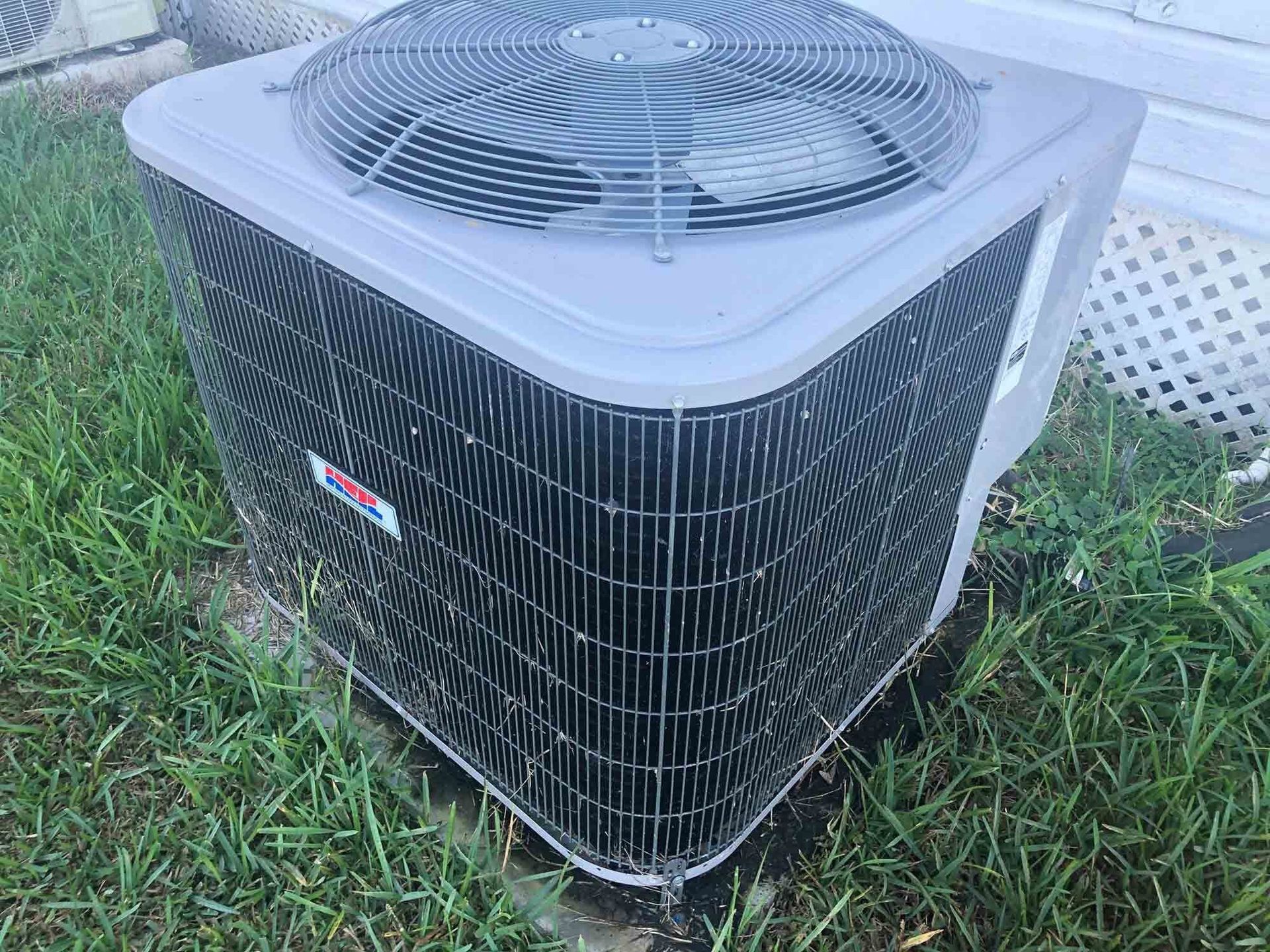 Air conditioning unit with fan on grass. Gray metal housing.