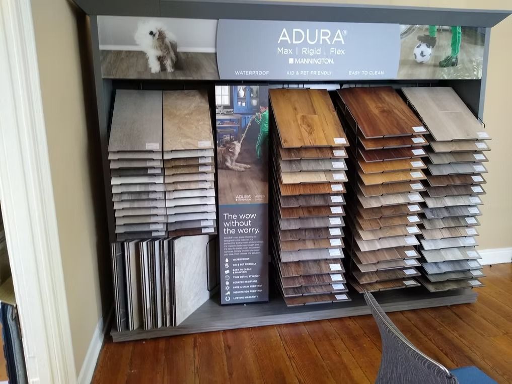 Display of ADURA flooring samples in various colors and styles.