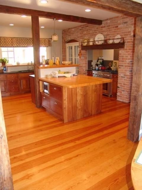 Wooden kitchen with wood floors, island, brick wall, and exposed beams.
