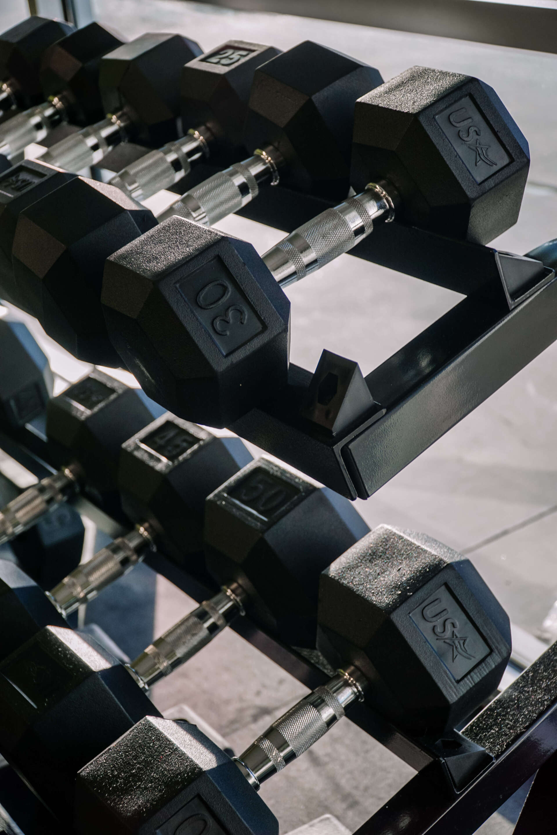 A row of dumbbells are lined up on a rack in a gym.