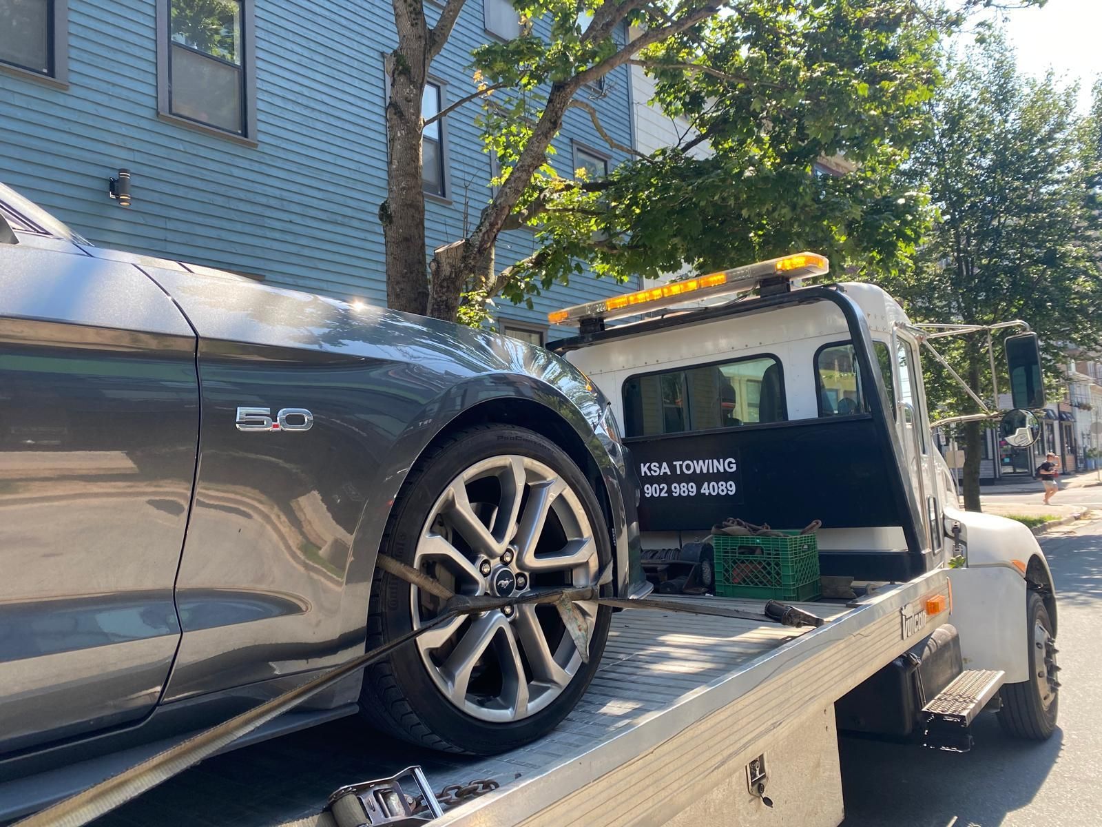 A gray mustang is being towed by a tow truck.