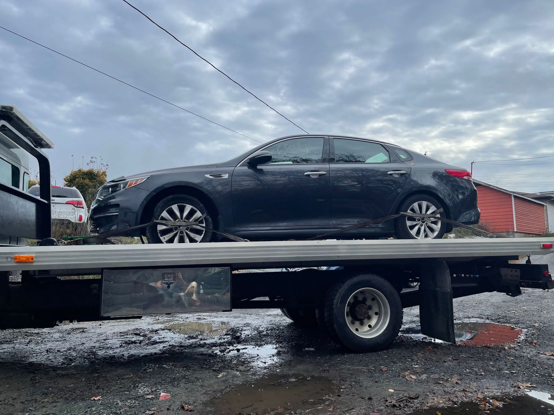 A black car is sitting on top of a tow truck.