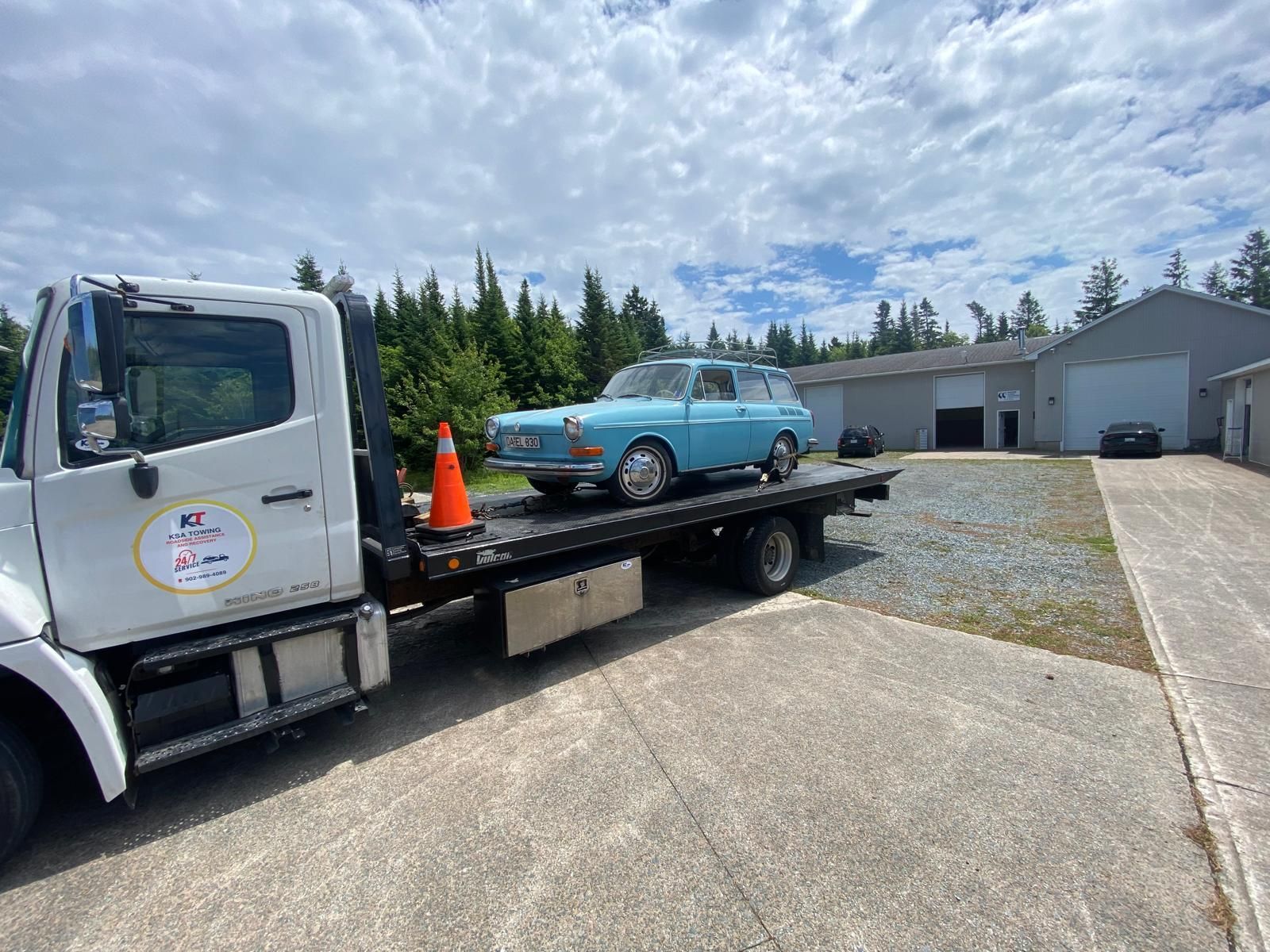 A blue car is being towed by a tow truck.