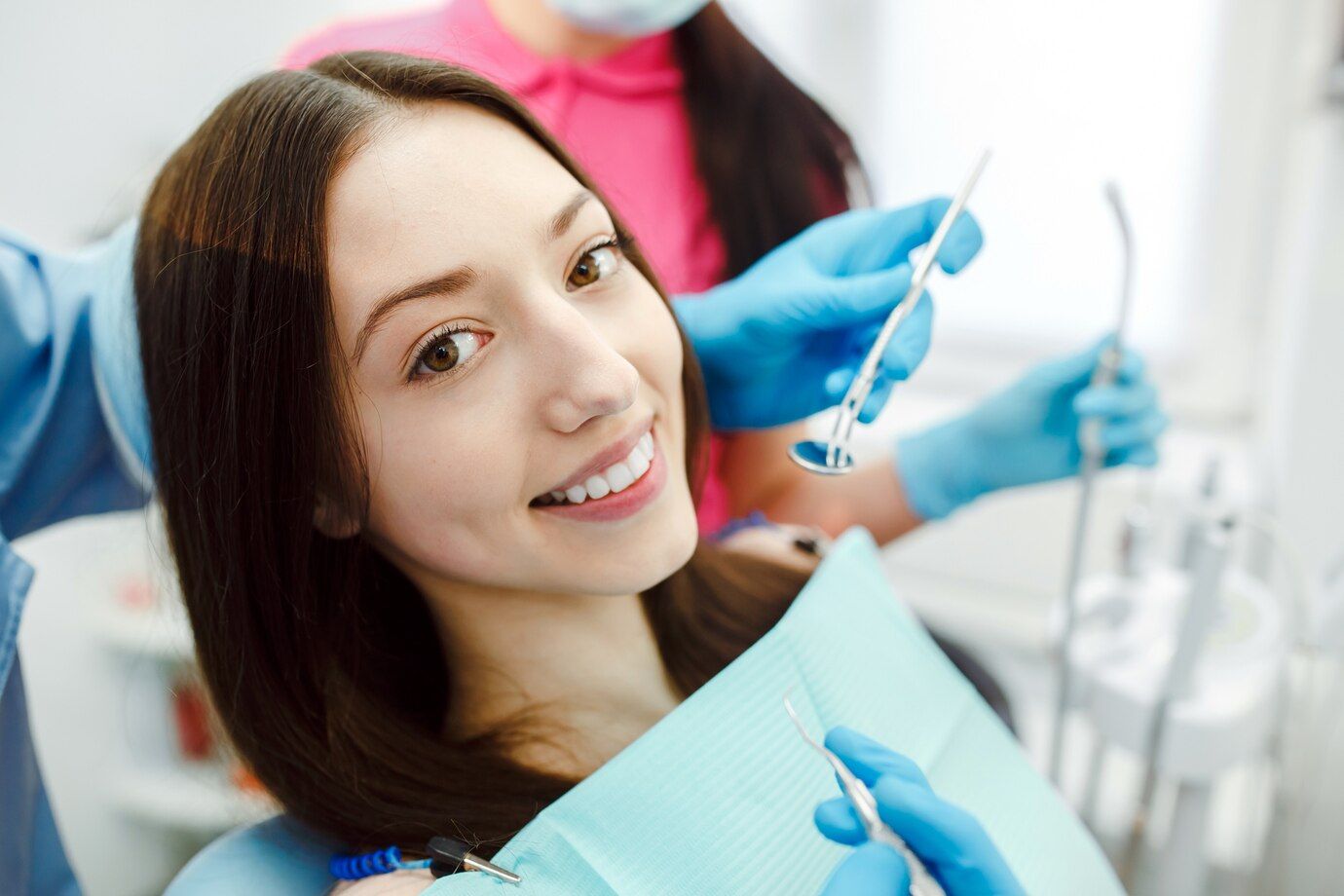 A woman is smiling while sitting in a dental chair.