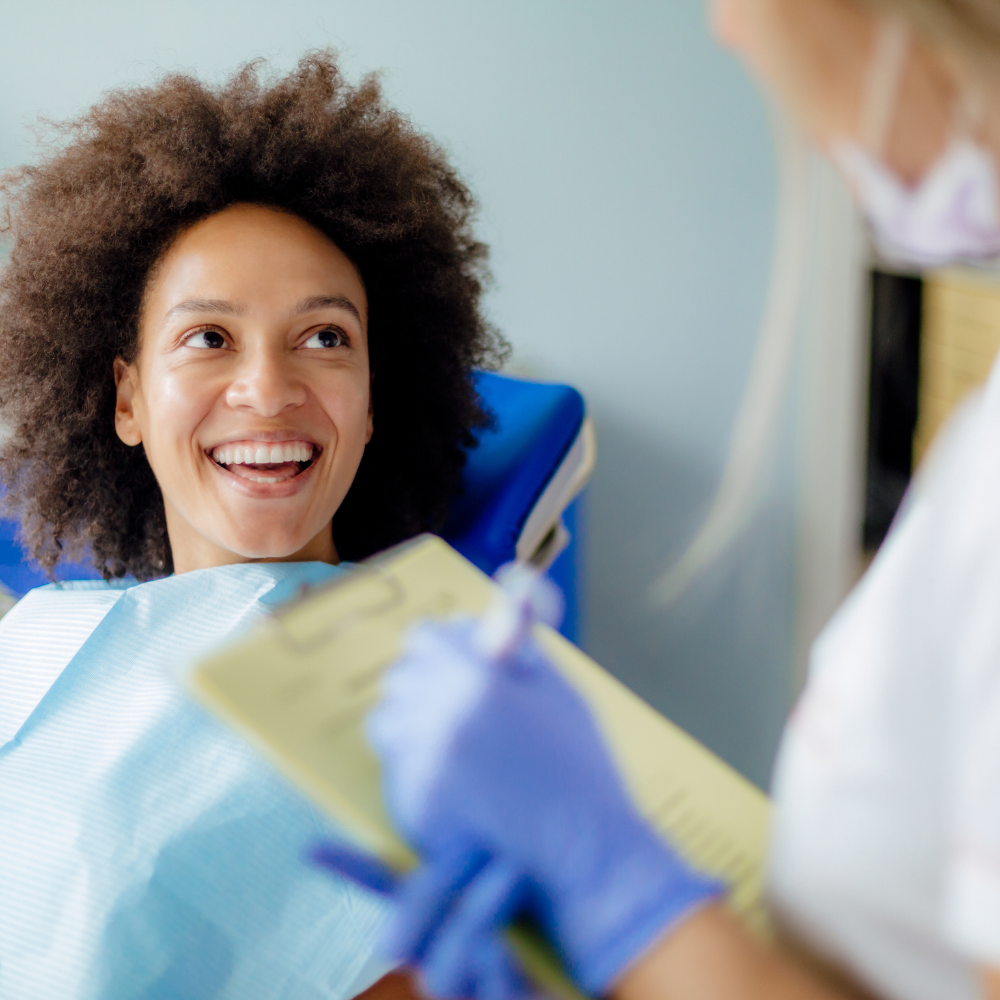 A woman is smiling while having her teeth examined by a dentist.