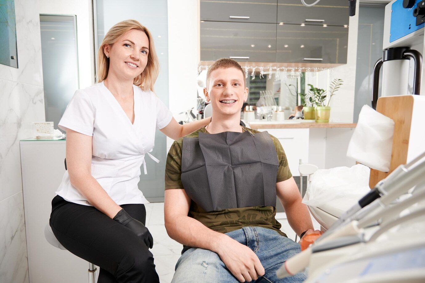 A woman is sitting next to a man in a dental chair.