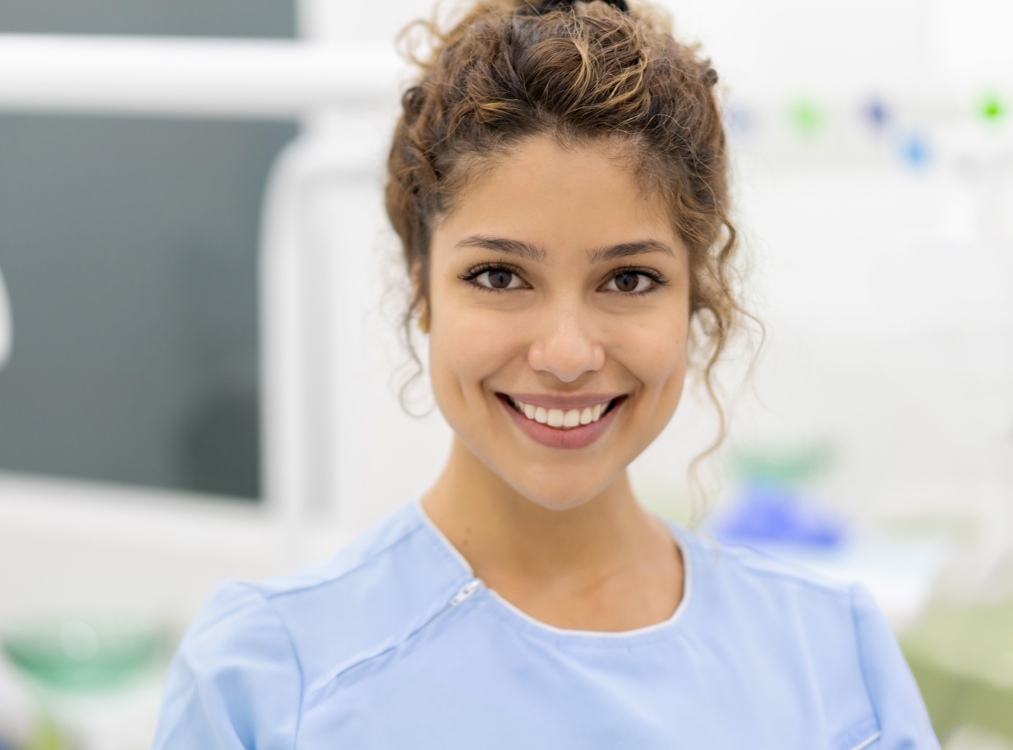 A female dentist is smiling for the camera in a dental office.