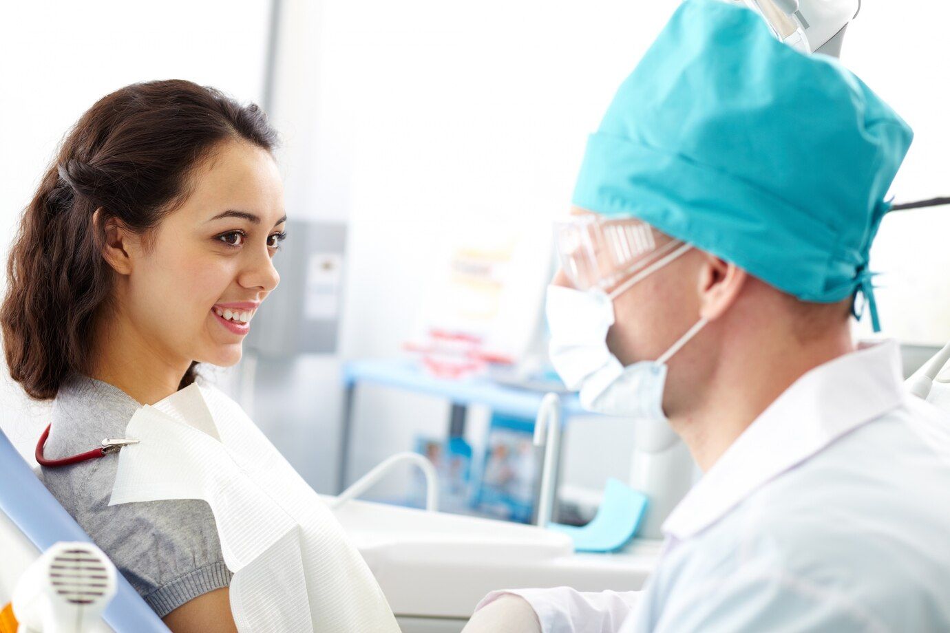 A woman is sitting in a dental chair talking to a dentist.