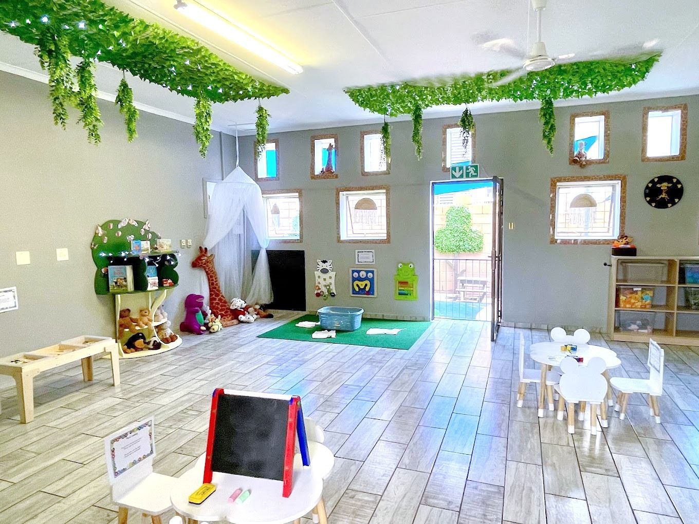 A classroom with tables and chairs and a green ceiling.