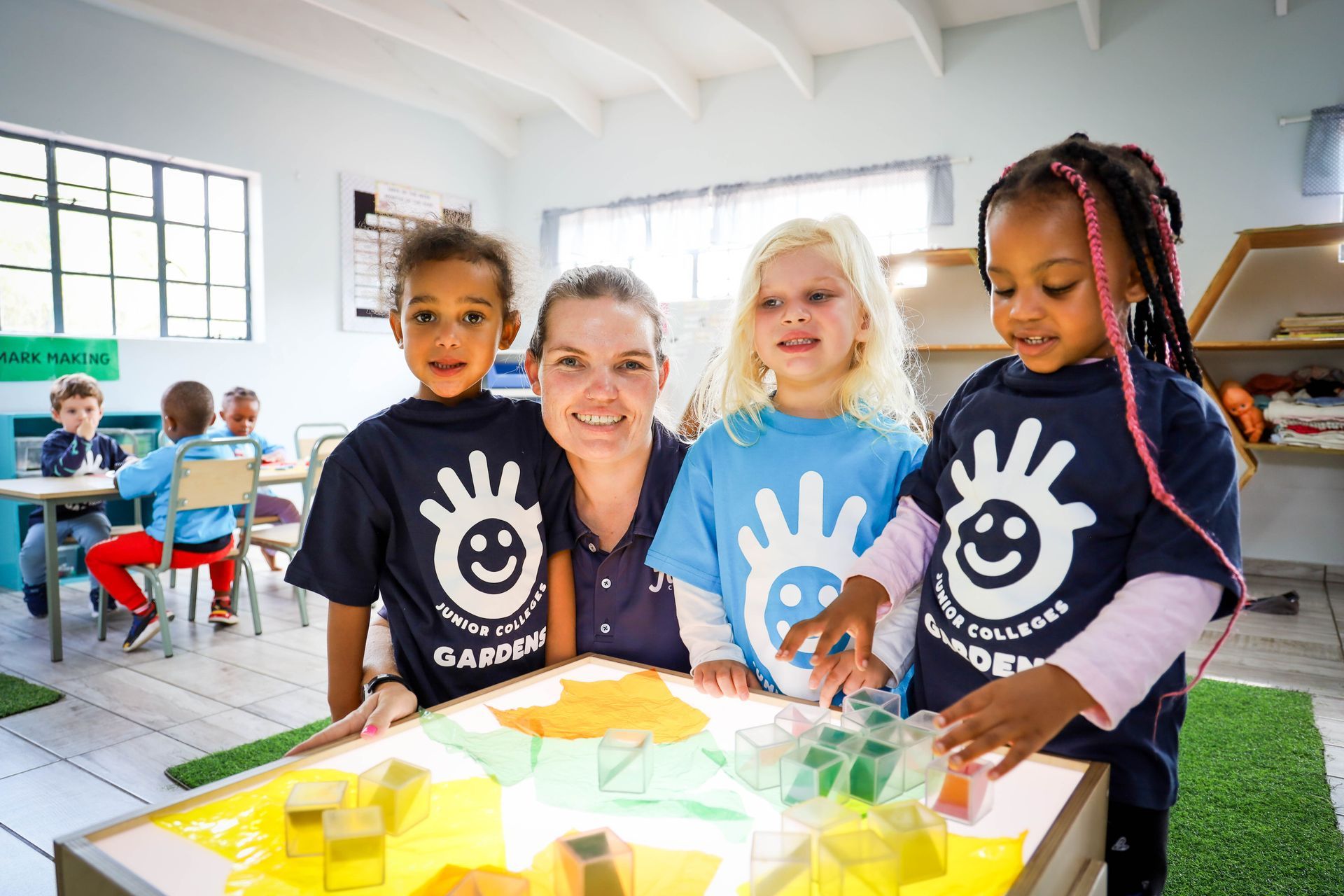 Three young children are playing in a large red bowl of water.