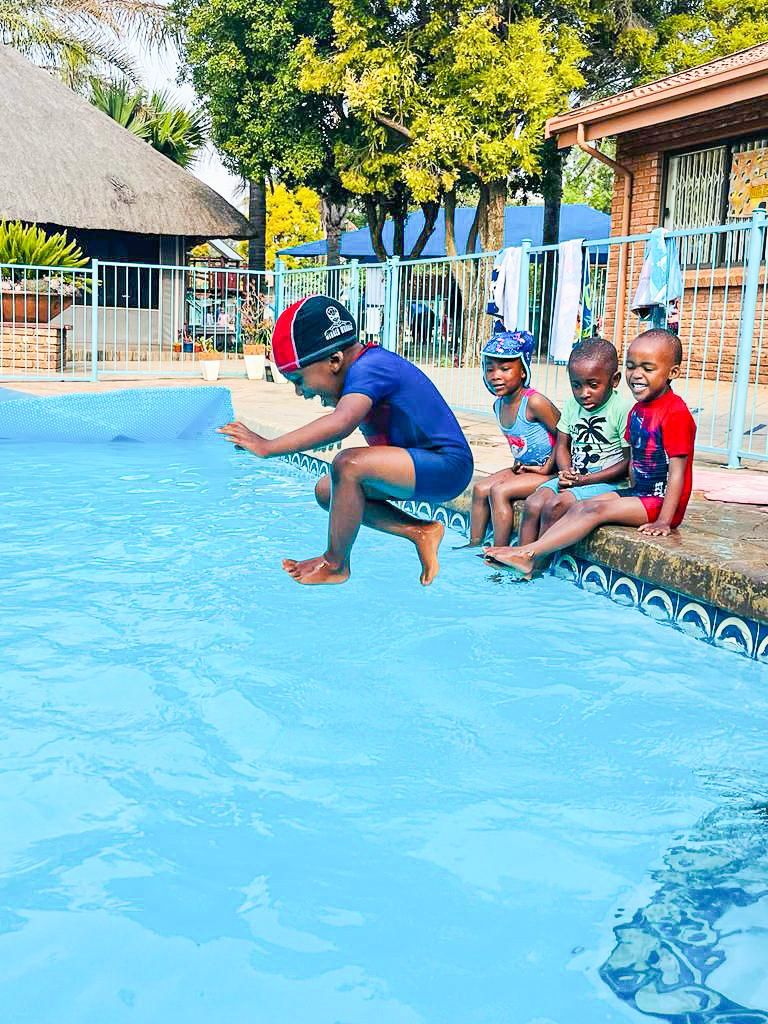 A group of children are sitting on the edge of a swimming pool.